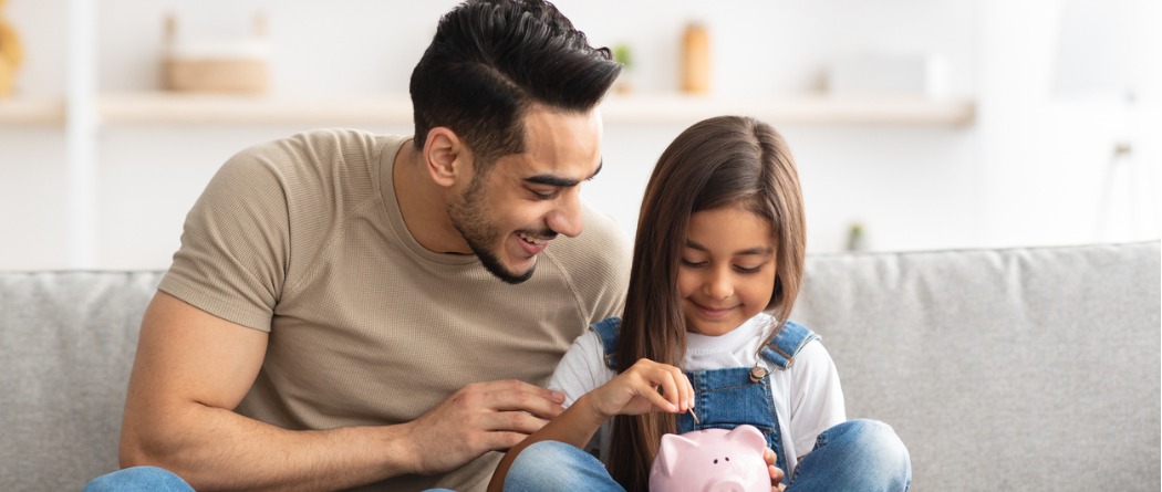 Father and Daughter putting money into a piggy bank