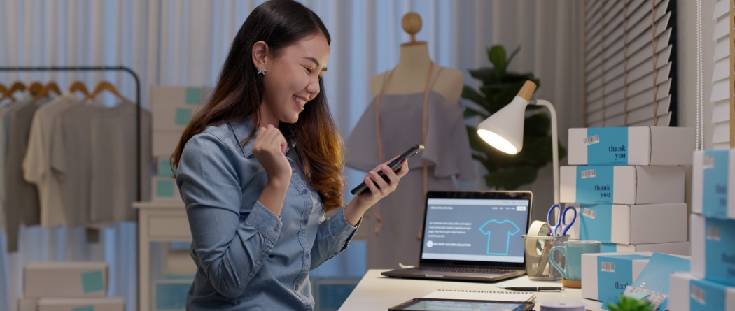 Business owner sitting in her office surrounded by products while on her phone