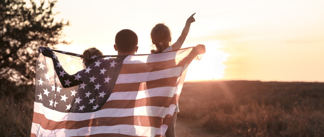 Children in the sunset holding the American flag